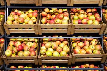 Fototapeta na wymiar Supermarket counter with wooden lug boxes full of transparent red-green apples