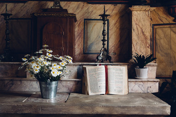 un autel d'église avec une bible ouverte et un bouquet de fleur. Un lieu de prière.  La...