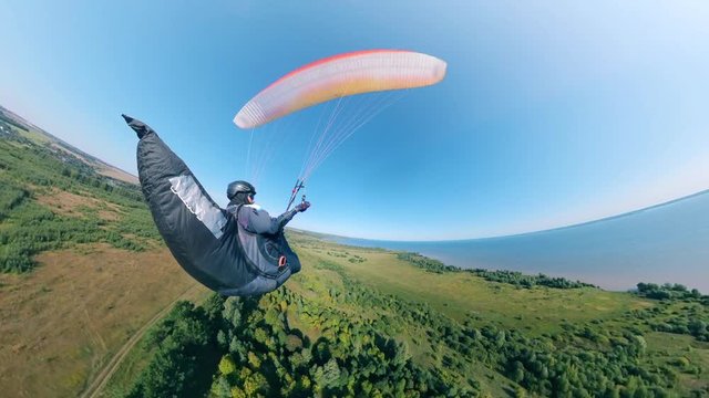 Green land and a person flying over it on the paraplane
