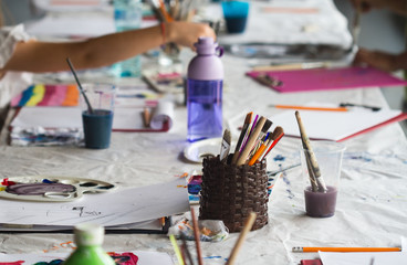 handful of painting brushes on a table in a brown jar