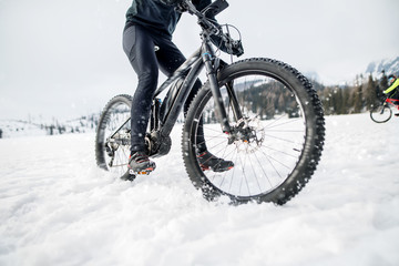 Fototapeta na wymiar Midsection of mountain biker riding in snow outdoors in winter.