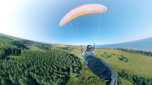 Backside view of a person having a paragliding flight