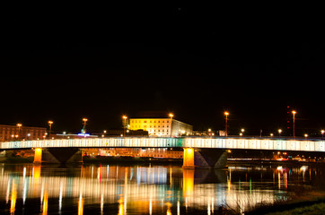 Fototapeta na wymiar Beautiful mesmerizing night scene panoramic view of Linz Nibelungen bridge over Danube river with golden lights colorful reflexions on water surface. Tourism in Austria traveling in Europe