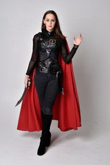 full length portrait of a pretty brunette woman wearing black leather fantasy costume with long red...