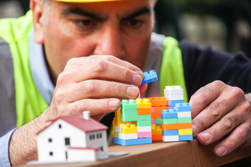 Absorbed civil engineer using multicoloured plastic construction toy building blocks