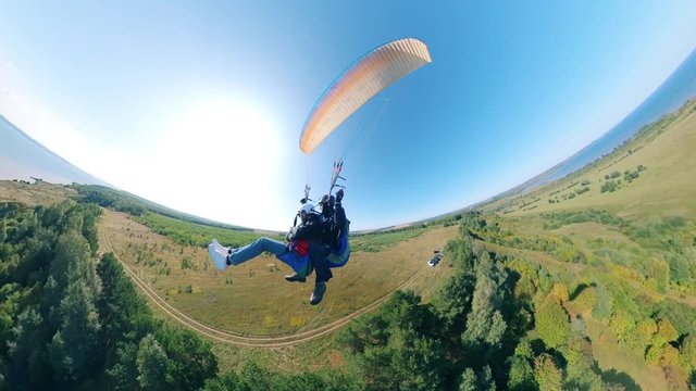 A couple is flying on the paraglider.