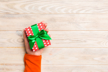 Woman hands give wrapped christmas or other holiday handmade present in colored paper . Present...