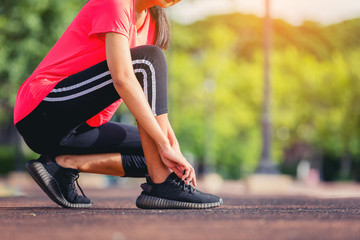 Crop image of woman runner lace her shoes and prepare to jogging with warm light