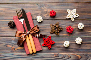 Top view of holiday set of fork and knife on wooden background. Close up of Christmas decorations and toys. New Year Eve concept