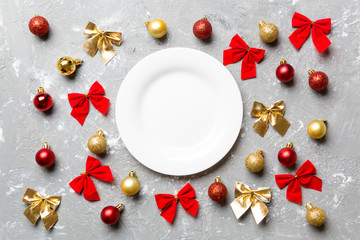 Naklejka na ściany i meble Top view of holiday dinner on cement background. Plate, baubles and bows. Christmas Eve concept