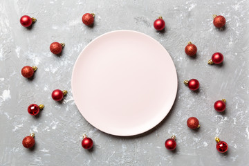Top view of festive plate with red baubles on cement background. Christmas decorations and toys. New Year advent concept
