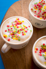 Coffee cups with foam decorated with colored stars.