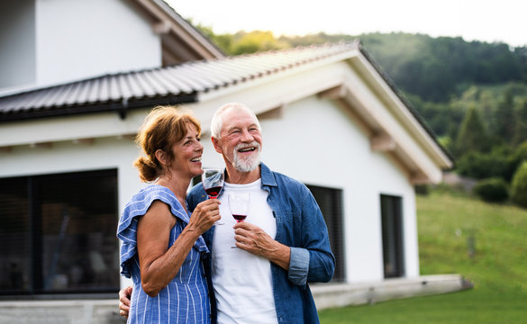 Portrait of senior couple with wine outdoors in backyard. - Powered by Adobe