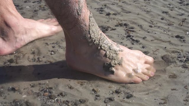 Adult Male Legs Covered In Sand Curling Toes To Drag Sand Back. Slow Motion
