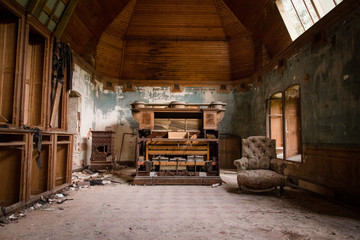 une salle abandonnée avec un vieux piano et un vieux fauteuil