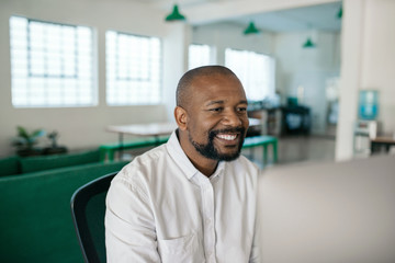 Smiling African American businessman using a computer in an office