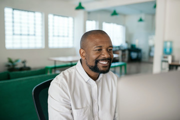 Obraz premium Smiling African American businessman using a computer in an office