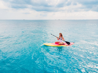 Attractive woman on stand up paddle board on a quiet blue ocean. Sup surfing in sea