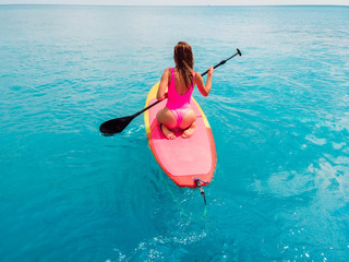 Attractive woman on stand up paddle board on a quiet blue ocean. Sup surfing in sea