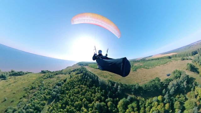 Paraplane flight of a person above the green trees