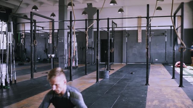 Male fitness instructor showing jumping exercise at loft plase. Jumping squats at gym. Effective exercises for great shape. lunch short workout. Back view to powerlifting jumps.