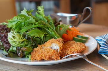 fried fish fillet with fresh vegetable on white plate