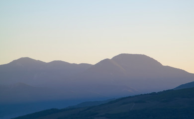 low mountains in mist at sunset. unspoilt hilly nature of haze away from man