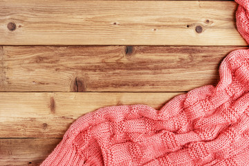 Pink handmade knitted fabric on wooden background. Space for text.