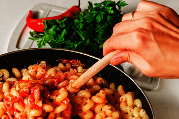 Traditional italian pasta with marinara sauce. Woman stirs a delicious homemade tomato sauce with pasta. Closeup