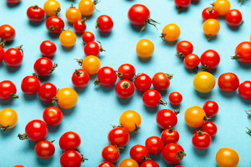 Red and yellow cherry tomatoes on blue background. Fresh bright organic vegetables.