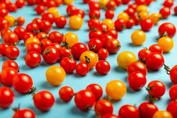 Red and yellow cherry tomatoes on blue background. Fresh bright organic vegetables.