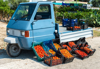 Small italian apo truck with tomatoes. Farmer sale tomatoes on the street in Italy.