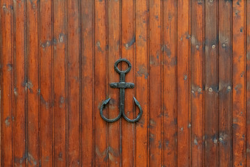 Black wrought iron anchor on wooden wall