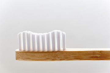 Closeup of a wooden toothbrush. Simple bamboo biodegradable eco toothbrush against a light...