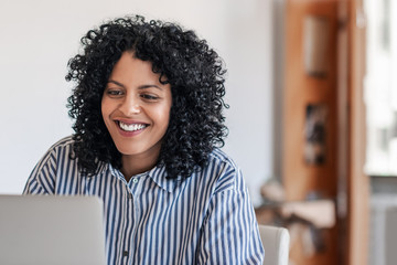 Laughing young female entrepreneur working at home on a laptop