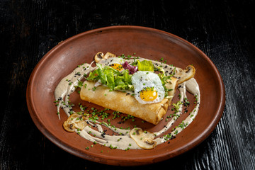 Rolled pancakes on top lies scrambled eggs. Beautiful clay plate-2.