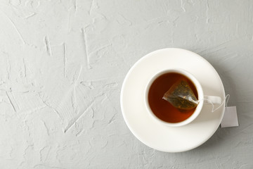 Cup of tea with tea bag on grey background, top view