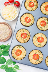 Savory muffins with quinoa, cheese and spinach topped with tomato, in  muffin tin, vertical, top view