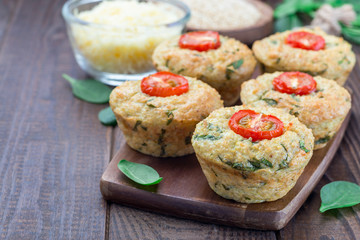 Savory muffins with quinoa, cheese and spinach topped with tomato, on wooden board, horizontal, copy space