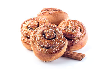 Four cinnamon buns and cinnamon sticks isolated on white background