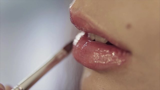 Female lips close-up. lipstick and lip gloss in makeup. Application. The concept of advertising lipstick, lip gloss, dentistry, plastic surgery, oral diseases, teeth