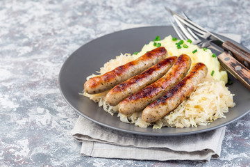 Roasted nuremberg sausages served with sour cabbage and mashed potatoes, horizontal, copy space