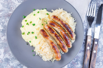 Roasted nuremberg sausages served with sour cabbage and mashed potatoes, horizontal, top view