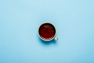 Metal cup with hot tea on a blue background. Flat lay, top view