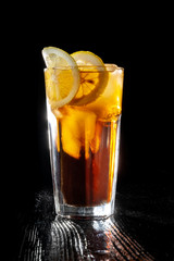 Long island ice tea. Standing on a varnished black table.