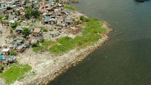 Slums with shacks of local residents and the river bank littered with garbage from above. Manila, Philippines. Slums in Manila, a top view. Sea pollution by household waste. Plastic trash on the beach