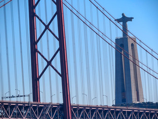 Obraz premium Christ the King Statue and the 25th April Bridge in Lisbon, Portugal. Famous landmark on river Tagus.