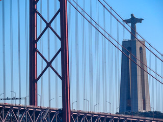 Naklejka premium Christ the King Statue and the 25th April Bridge in Lisbon, Portugal. Famous landmark on river Tagus.