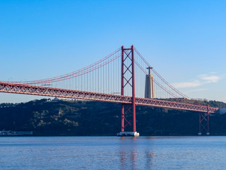 Christ the King Statue and the 25th April Bridge in Lisbon, Portugal. Famous landmark on river Tagus.