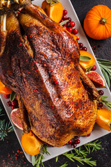 Christmas baked duck with herbs and fruits on gray plate, dark background.